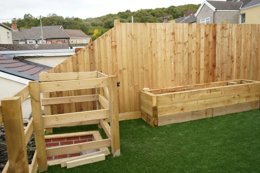 New timber fencing and raised planters around an artificial lawn
