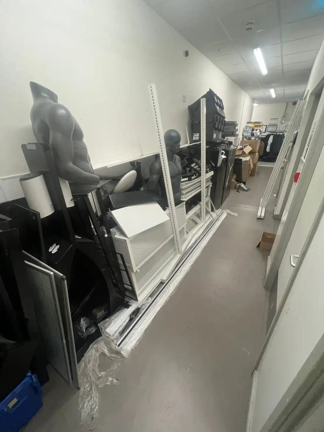 Dismantled shop fittings lined up along a corridor
