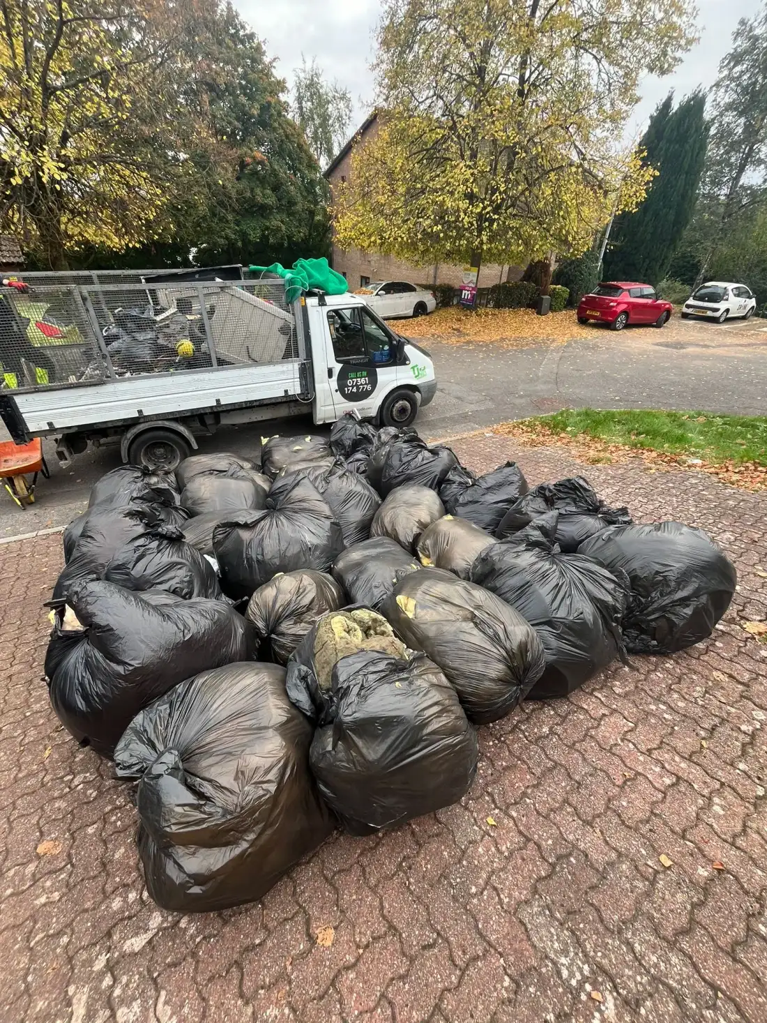 Black bags of household waste stacked beside the TJB tipper truck